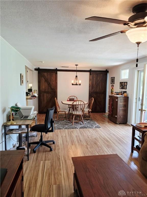 1008 Terracewood Dr, Englewood, OH 45322 - living area with a barn door, light wood-style floors, a textured ceiling, crown molding, and ceiling fan