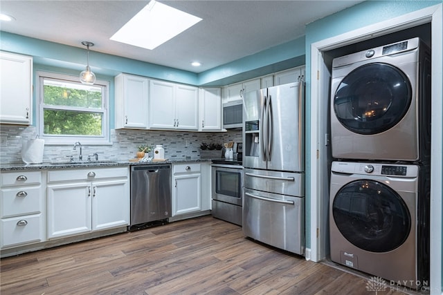 1172 Bay Ln, Beavercreek, OH 45430 - kitchen featuring appliances with stainless steel finishes, estacked washer and dryer, a sink, a skylight, and white cabinets