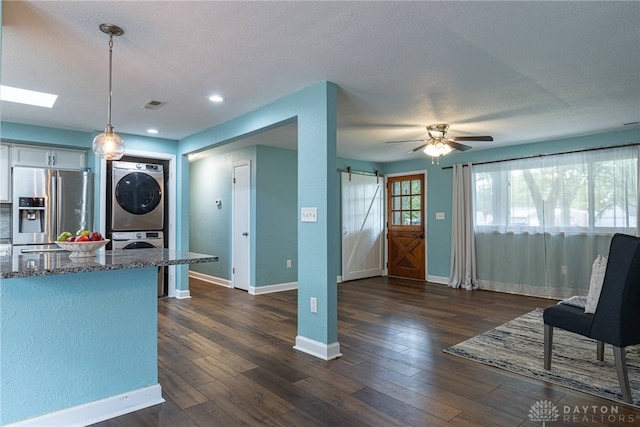 1172 Bay Ln, Beavercreek, OH 45430 - kitchen featuring stainless steel fridge with ice dispenser, stacked washing machine and dryer, a barn door, dark stone countertops, and baseboards