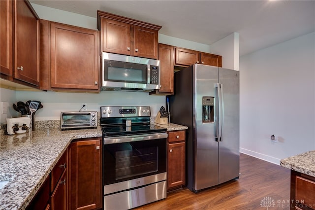 6709 Crystal Harbour Dr, Middletown, OH 45042 - kitchen featuring stainless steel appliances, dark wood-style floors, light stone countertops, baseboards, and brown cabinets