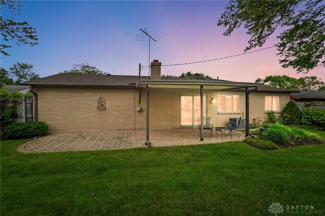 348 Cambridge Dr, Fairborn, OH 45324 - back of property at dusk featuring a patio, a chimney, brick siding, and central air condition unit