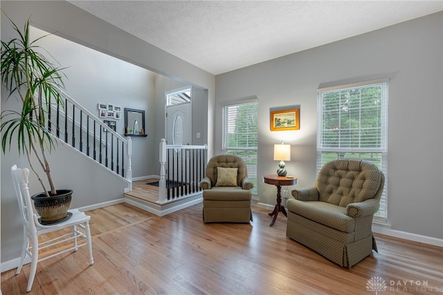 989 Brooke Ln, Xenia, OH 45385 - sitting room featuring wood finished floors, plenty of natural light, stairs, baseboards, and a textured ceiling
