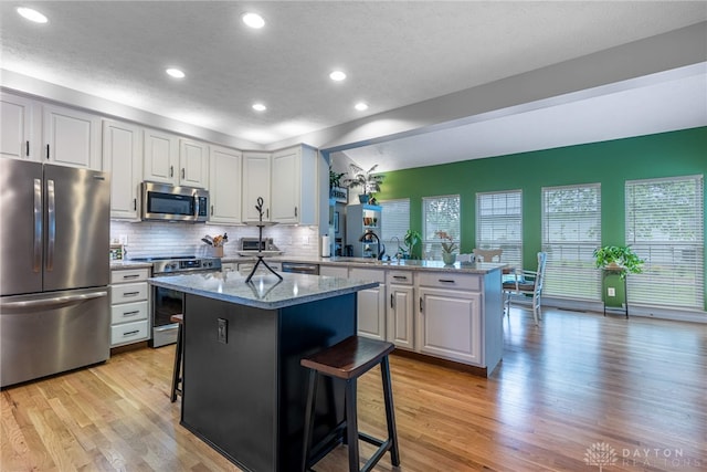 989 Brooke Ln, Xenia, OH 45385 - kitchen with stainless steel appliances, a sink, a peninsula, a kitchen breakfast bar, and light wood-type flooring