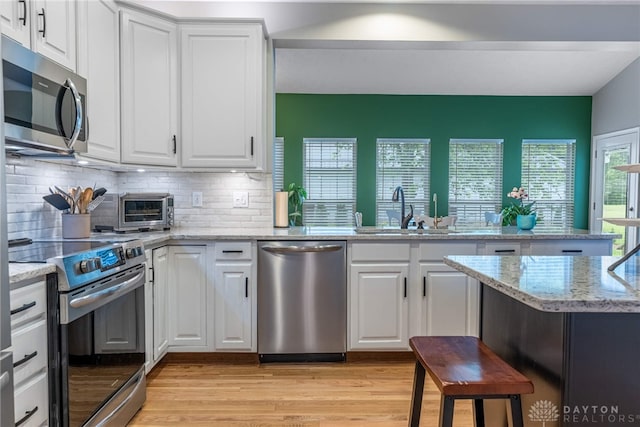989 Brooke Ln, Xenia, OH 45385 - kitchen featuring stainless steel appliances, light wood-style floors, a sink, and white cabinetry