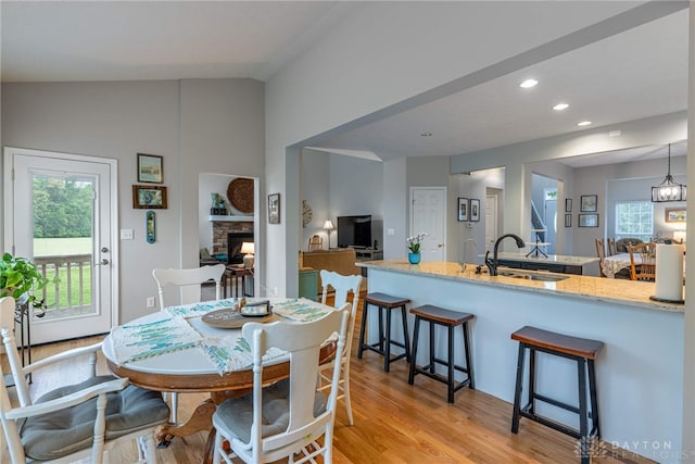 989 Brooke Ln, Xenia, OH 45385 - dining space featuring a fireplace, light wood-style flooring, vaulted ceiling, and recessed lighting