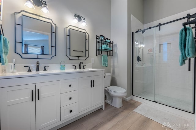 989 Brooke Ln, Xenia, OH 45385 - full bathroom featuring wood finished floors, toilet, double vanity, and a shower stall