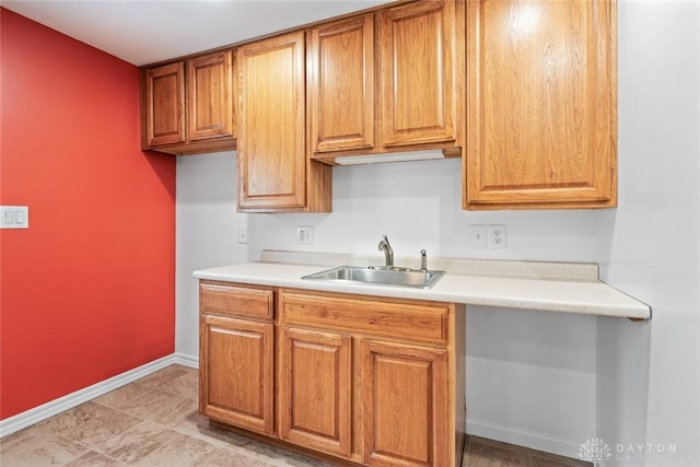2707 Rockledge Trl, Beavercreek, OH 45430 - kitchen featuring a sink, light countertops, baseboards, and brown cabinetry