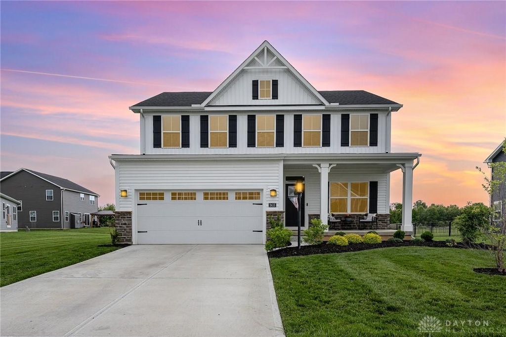 2415 David Grey Cir, Dayton, OH 45434 - view of front facade featuring covered porch, a front yard, board and batten siding, an attached garage, and driveway