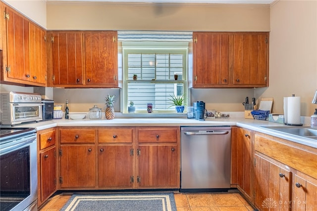 54 Beverly Pl, Oakwood, OH 45419 - kitchen with stainless steel appliances, light countertops, brown cabinetry, crown molding, and light tile patterned floors