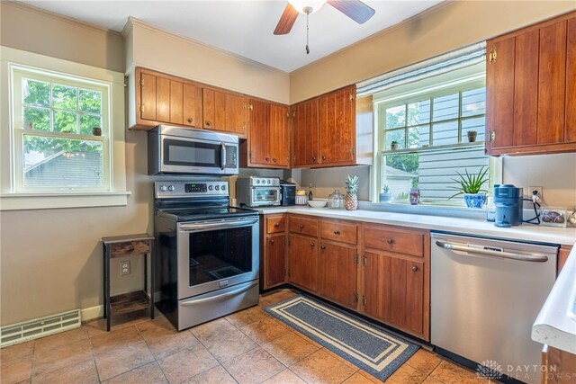 54 Beverly Pl, Oakwood, OH 45419 - kitchen with appliances with stainless steel finishes, light countertops, brown cabinets, healthy amount of natural light, and crown molding