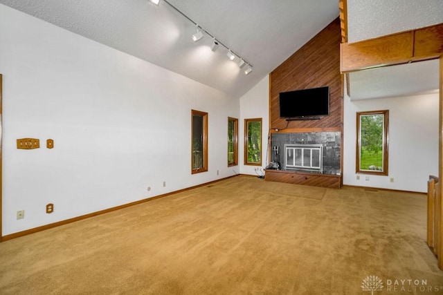 4723 Rosedale Rd, Middletown, OH 45042 - unfurnished living room featuring light colored carpet, a large fireplace, rail lighting, baseboards, and high vaulted ceiling