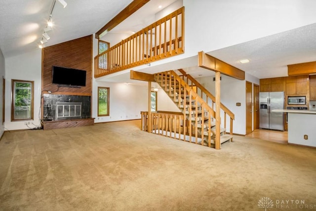 4723 Rosedale Rd, Middletown, OH 45042 - unfurnished living room with light carpet, high vaulted ceiling, rail lighting, a large fireplace, and stairway
