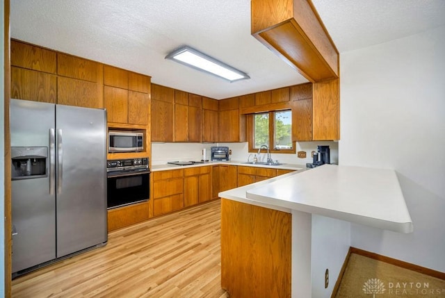 4723 Rosedale Rd, Middletown, OH 45042 - kitchen featuring black appliances, a peninsula, a sink, brown cabinetry, and light countertops