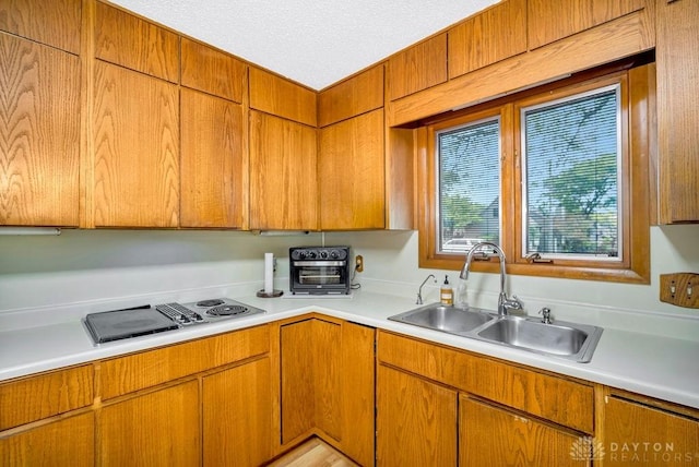 4723 Rosedale Rd, Middletown, OH 45042 - kitchen with a sink, light countertops, brown cabinets, stovetop with downdraft, and a textured ceiling