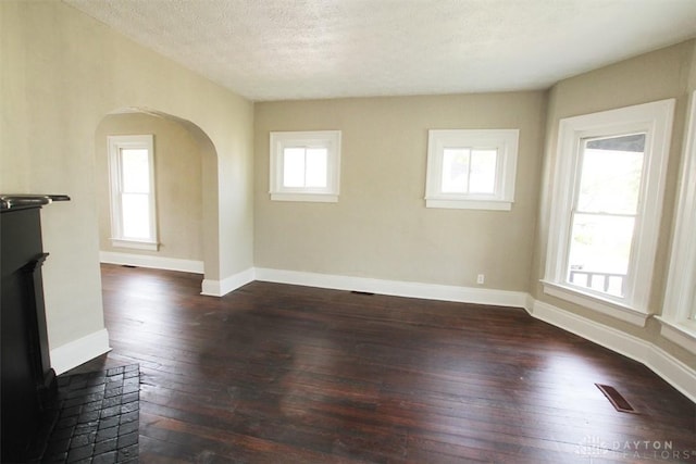 1716 Xenia Ave, Dayton, OH 45410 - unfurnished living room with dark wood finished floors, arched walkways, plenty of natural light, a textured ceiling, and baseboards