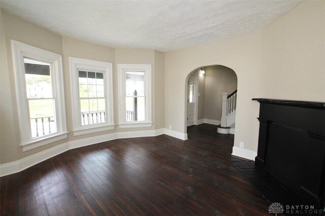 1716 Xenia Ave, Dayton, OH 45410 - unfurnished living room with arched walkways, hardwood / wood-style floors, baseboards, stairway, and a textured ceiling