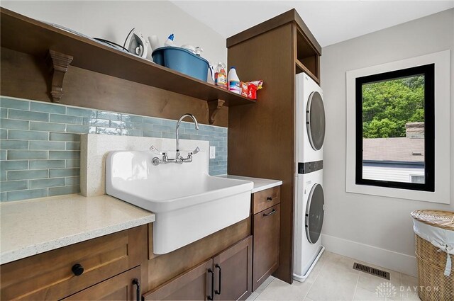 1000 Paradrome St, Cincinnati, OH 45202 - laundry area with estacked washer and dryer, cabinet space, light tile patterned floors, and baseboards