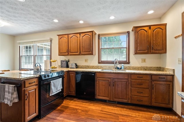 1747 Maple Ln, Beavercreek, OH 45432 - kitchen featuring black appliances, a sink, a peninsula, a textured ceiling, and dark wood-style flooring