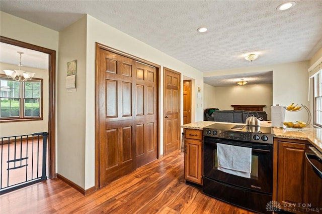1747 Maple Ln, Beavercreek, OH 45432 - kitchen with black electric range, dark wood-style floors, a textured ceiling, a chandelier, and light stone countertops
