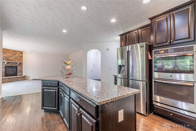 8730 Dowd Ct, Washington Twp, OH 45458 - kitchen featuring stainless steel appliances, a textured ceiling, a center island, hardwood / wood-style floors, and dark brown cabinetry