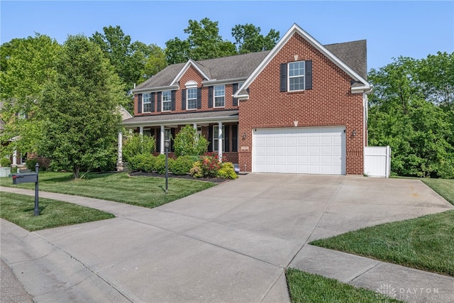 8730 Dowd Ct, Washington Twp, OH 45458 - colonial home with a front lawn, an attached garage, a porch, driveway, and brick siding