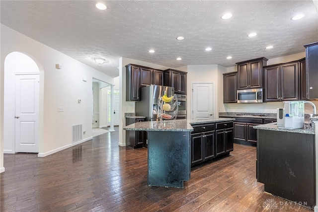8730 Dowd Ct, Washington Twp, OH 45458 - kitchen featuring appliances with stainless steel finishes, a center island, dark wood finished floors, light stone countertops, and recessed lighting