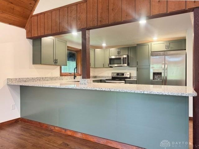 5565 Short Rd, New Carlisle, OH 45344 - kitchen with appliances with stainless steel finishes, a peninsula, lofted ceiling, baseboards, and dark wood-type flooring