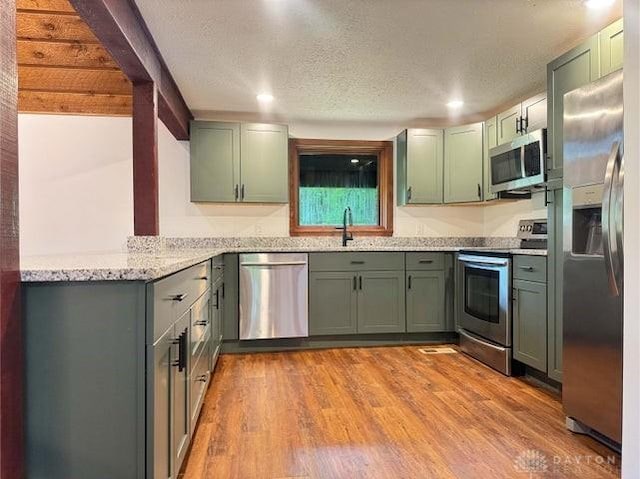 5565 Short Rd, New Carlisle, OH 45344 - kitchen with appliances with stainless steel finishes, green cabinets, light stone countertops, wood finished floors, and a textured ceiling