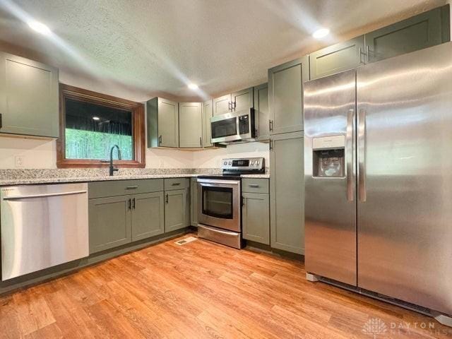 5565 Short Rd, New Carlisle, OH 45344 - kitchen with appliances with stainless steel finishes, light wood finished floors, recessed lighting, and light stone countertops