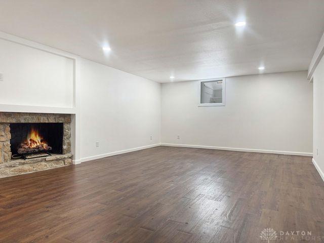 5565 Short Rd, New Carlisle, OH 45344 - unfurnished living room with dark wood-type flooring, a stone fireplace, recessed lighting, and baseboards