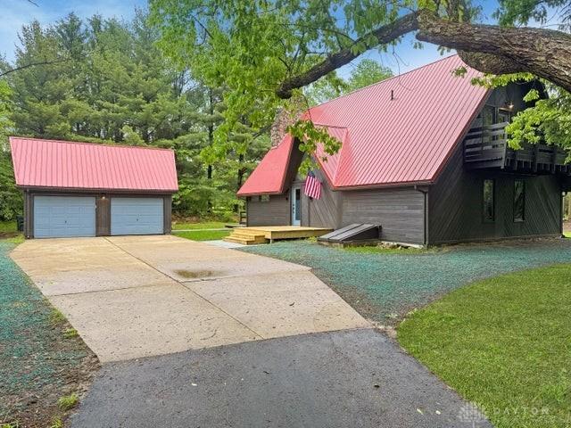 5565 Short Rd, New Carlisle, OH 45344 - view of property exterior with metal roof, an outdoor structure, a garage, and a lawn