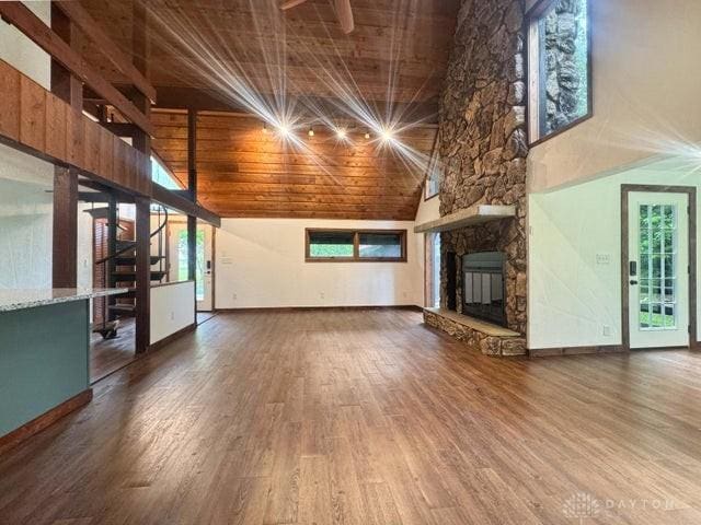5565 Short Rd, New Carlisle, OH 45344 - unfurnished living room with wood ceiling, high vaulted ceiling, a stone fireplace, wood finished floors, and baseboards