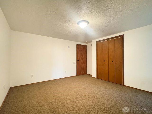 5565 Short Rd, New Carlisle, OH 45344 - unfurnished bedroom featuring a textured ceiling and carpet flooring
