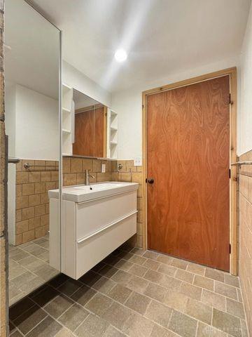 5565 Short Rd, New Carlisle, OH 45344 - bathroom with tile walls, vanity, and wainscoting