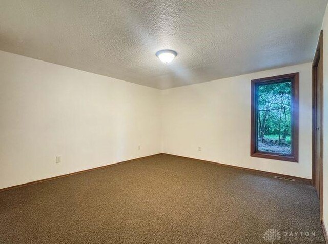 5565 Short Rd, New Carlisle, OH 45344 - spare room featuring dark carpet, a textured ceiling, and baseboards