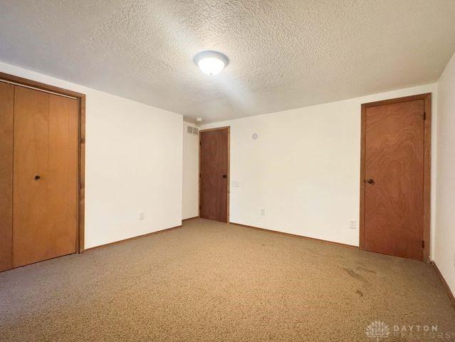 5565 Short Rd, New Carlisle, OH 45344 - unfurnished bedroom with a textured ceiling and carpet floors