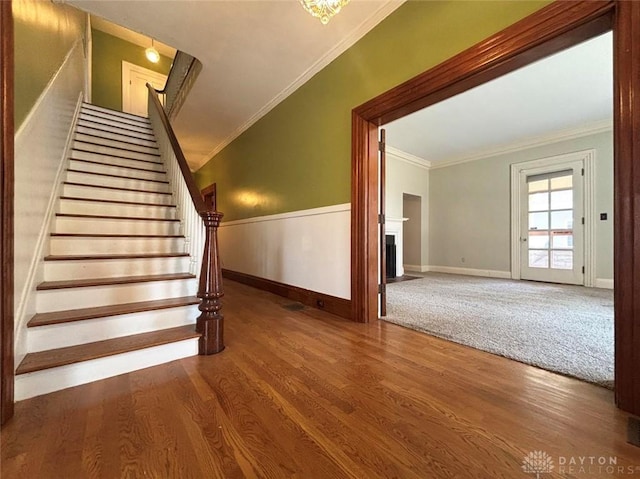 142 W Church St, Xenia, OH 45385 - staircase with ornamental molding, wood finished floors, a wainscoted wall, a fireplace, and baseboards