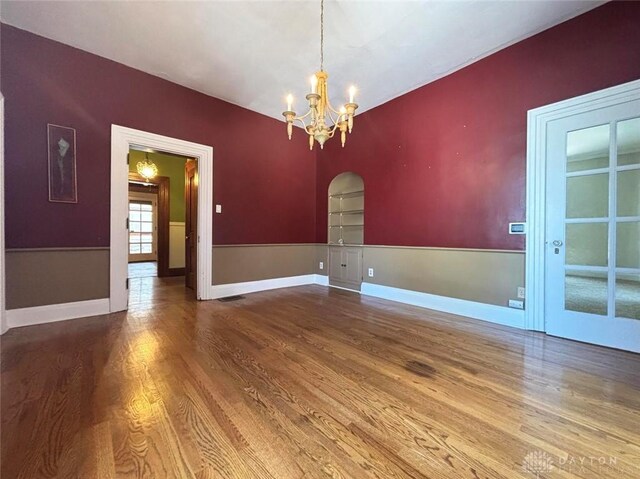 142 W Church St, Xenia, OH 45385 - empty room featuring wood finished floors, built in shelves, a chandelier, and arched walkways