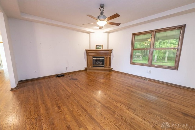 9062 Adam Ln, Waynesville, OH 45068 - unfurnished living room with a glass covered fireplace, wood finished floors, a ceiling fan, and baseboards