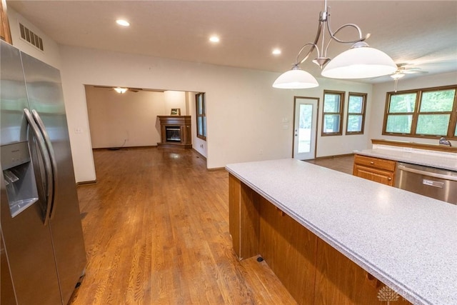 9062 Adam Ln, Waynesville, OH 45068 - kitchen with appliances with stainless steel finishes, a ceiling fan, a fireplace, light countertops, and brown cabinetry