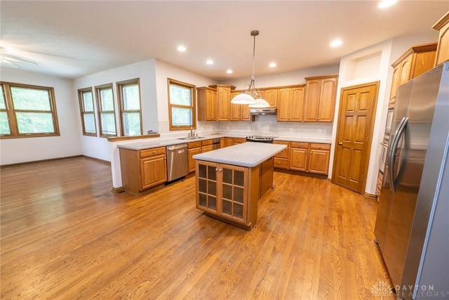 9062 Adam Ln, Waynesville, OH 45068 - kitchen with appliances with stainless steel finishes, light countertops, a kitchen island, light wood finished floors, and a sink