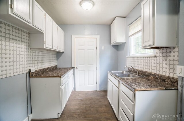 3108 Ohio Ave, Middletown, OH 45042 - kitchen with a sink, dark wood-style floors, dark countertops, white cabinetry, and wallpapered walls