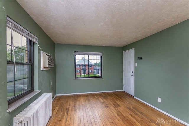515 Aberdeen Ave, Dayton, OH 45419 - unfurnished room featuring radiator, wood-type flooring, healthy amount of natural light, a textured ceiling, and an AC wall unit