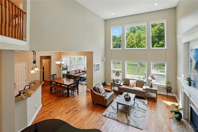 10041 Meadow Woods Ln, Washington Twp, OH 45458 - living room with a high ceiling, plenty of natural light, light wood-style floors, a chandelier, and baseboards