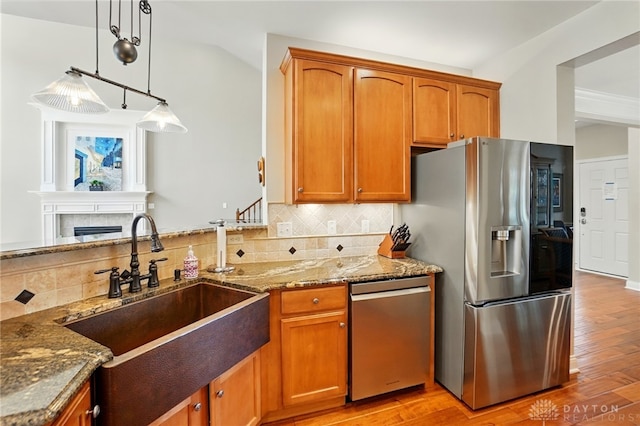 10041 Meadow Woods Ln, Washington Twp, OH 45458 - kitchen featuring appliances with stainless steel finishes, a sink, stone countertops, decorative backsplash, and light wood-type flooring
