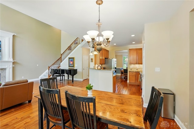 10041 Meadow Woods Ln, Washington Twp, OH 45458 - dining space featuring a chandelier, light wood-style flooring, stairway, recessed lighting, and baseboards
