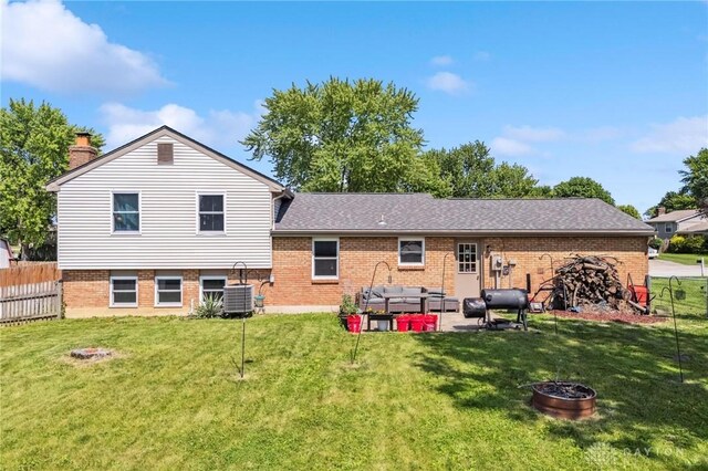 813 Ridge Rd, Englewood, OH 45322 - back of property featuring brick siding, a patio area, roof with shingles, an outdoor living space with a fire pit, and central AC