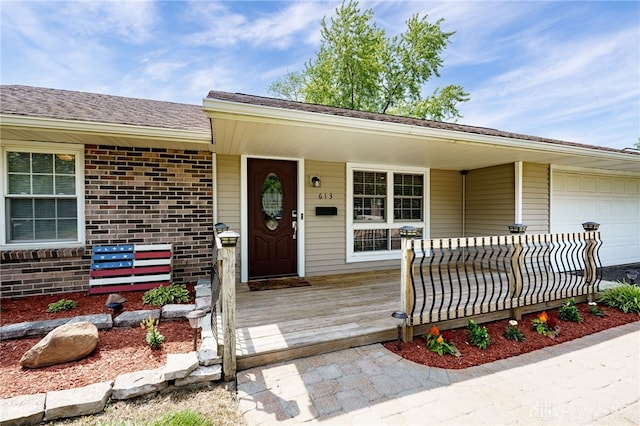 613 Spinning Rd, New Carlisle, OH 45344 - doorway to property featuring a garage, brick siding, and covered porch