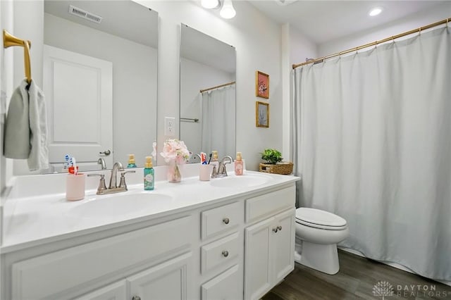 2550 Bellevue Dr, Batavia, OH 45103 - bathroom featuring double vanity, toilet, wood finished floors, a shower with curtain, and recessed lighting