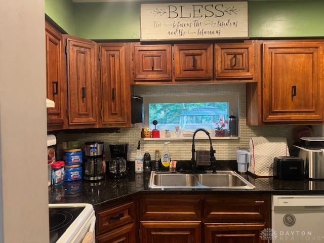 224 S Wolf Creek St, Brookville, OH 45309 - kitchen featuring white dishwasher, a sink, range, decorative backsplash, and dark countertops